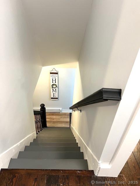 staircase with wood finished floors and baseboard heating