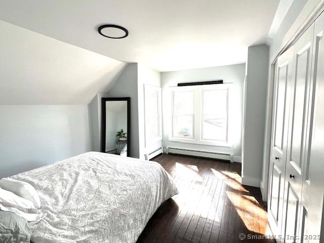 bedroom featuring dark wood-type flooring, baseboard heating, and lofted ceiling