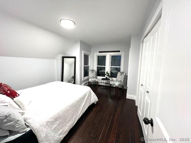 bedroom with dark wood finished floors, baseboards, and lofted ceiling