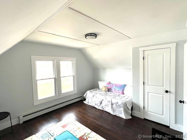 bedroom featuring lofted ceiling, wood finished floors, baseboards, and baseboard heating