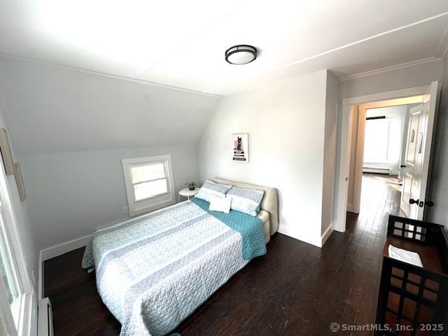 bedroom with baseboards, lofted ceiling, and dark wood-type flooring