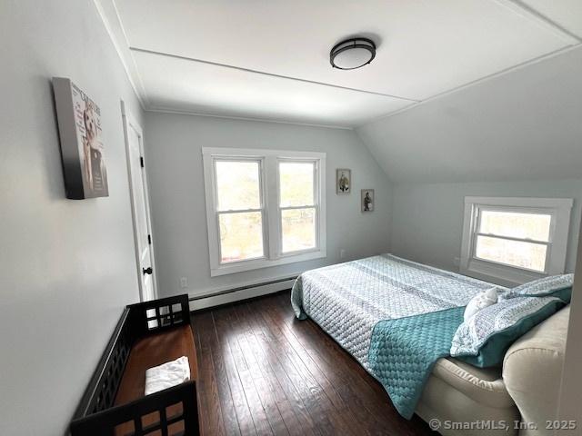 bedroom featuring baseboard heating, lofted ceiling, and hardwood / wood-style flooring