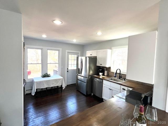 kitchen featuring a sink, dark wood-style flooring, appliances with stainless steel finishes, white cabinets, and a baseboard radiator