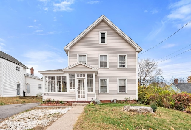 back of property featuring a lawn and a sunroom