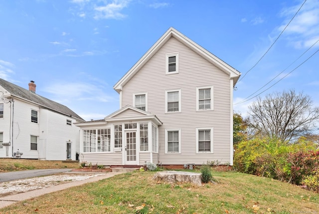 rear view of house with a lawn and a sunroom