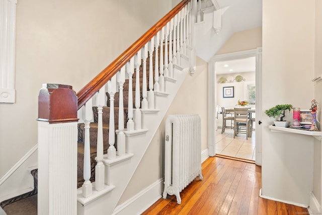 staircase featuring hardwood / wood-style floors, radiator, and baseboards