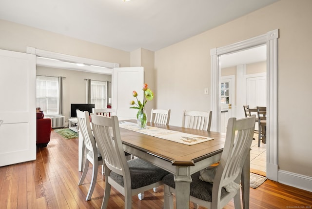 dining room with radiator, baseboards, and light wood finished floors