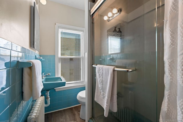 full bathroom featuring wood finished floors, radiator heating unit, a stall shower, tile walls, and toilet