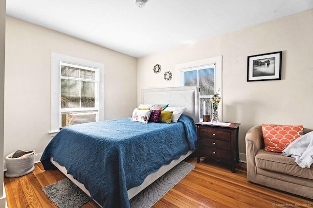 bedroom featuring cooling unit, wood finished floors, and baseboards