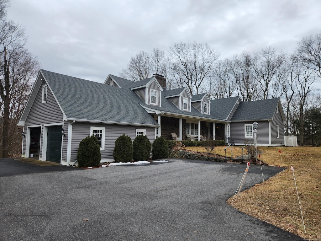 new england style home featuring a garage and roof with shingles