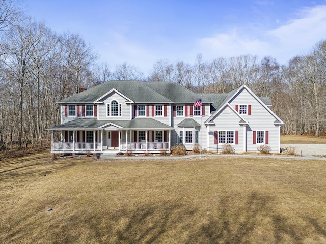 view of front facade featuring a chimney, covered porch, and a front lawn