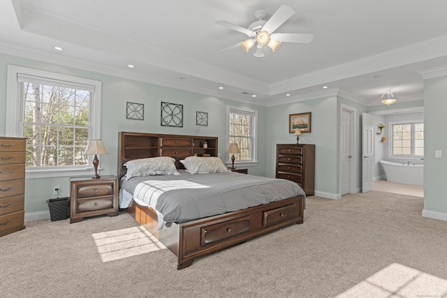 carpeted bedroom with a tray ceiling, recessed lighting, crown molding, and baseboards