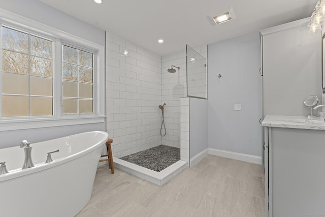 bathroom with vanity, baseboards, a freestanding tub, recessed lighting, and walk in shower