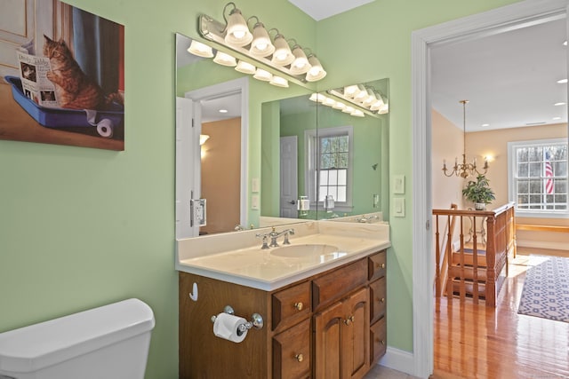 bathroom with baseboards, toilet, a chandelier, and vanity