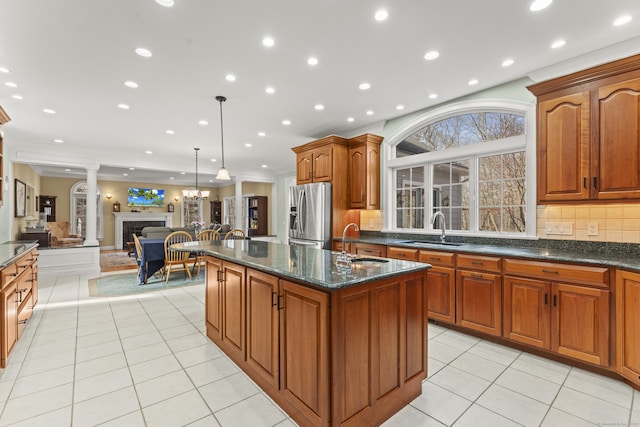 kitchen featuring light tile patterned floors, stainless steel fridge, a kitchen island with sink, and a sink