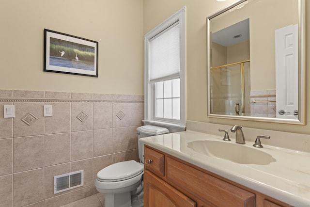 full bathroom with vanity, visible vents, a stall shower, tile walls, and toilet