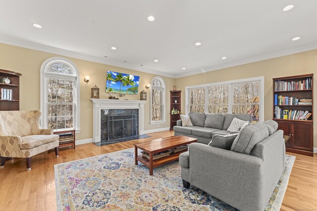 living area with a high end fireplace, crown molding, and wood finished floors