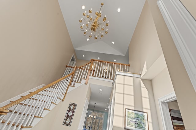 stairs with an inviting chandelier, recessed lighting, baseboards, and high vaulted ceiling