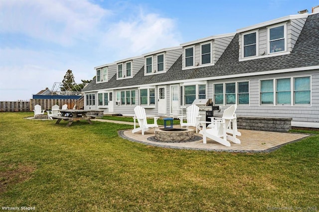 rear view of property featuring a patio area, a lawn, an outdoor fire pit, and fence