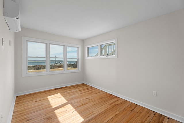 empty room with baseboards, wood-type flooring, and an AC wall unit