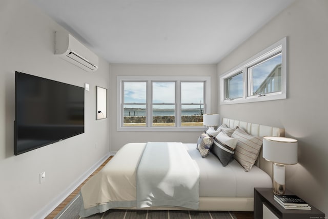 bedroom with baseboards, a wall unit AC, and wood finished floors