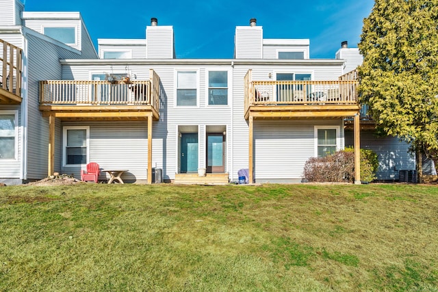 rear view of house featuring a balcony, central AC unit, a chimney, and a yard