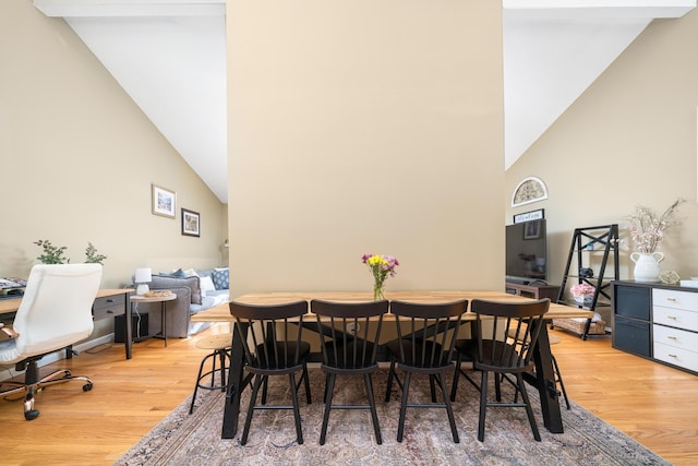 dining room featuring high vaulted ceiling and light wood-style floors