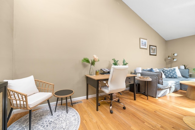 office space featuring light wood-type flooring, baseboards, visible vents, and vaulted ceiling