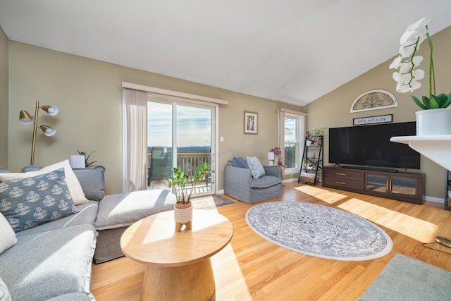 living area with baseboards, lofted ceiling, and wood finished floors