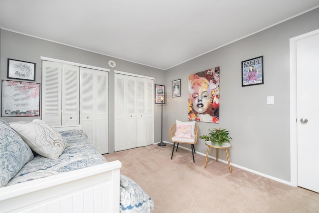 bedroom featuring baseboards, multiple closets, and light colored carpet