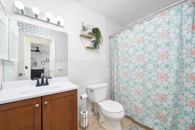 ensuite bathroom featuring a wainscoted wall, toilet, a ceiling fan, tile walls, and tile patterned flooring