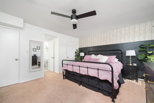 bedroom with light colored carpet, ceiling fan, an accent wall, and wallpapered walls