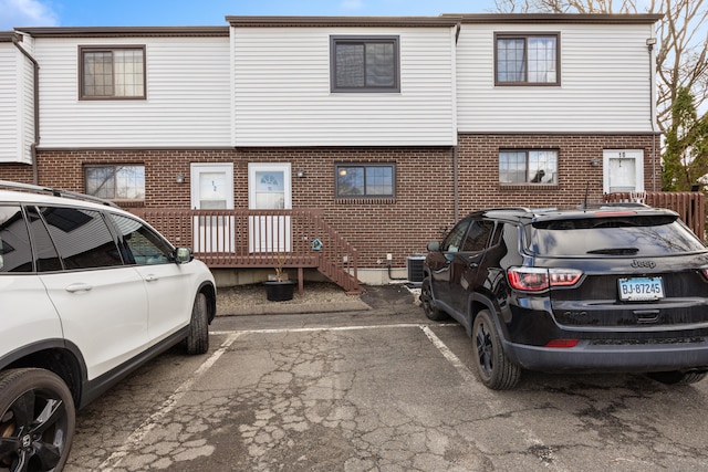 back of house with uncovered parking and brick siding