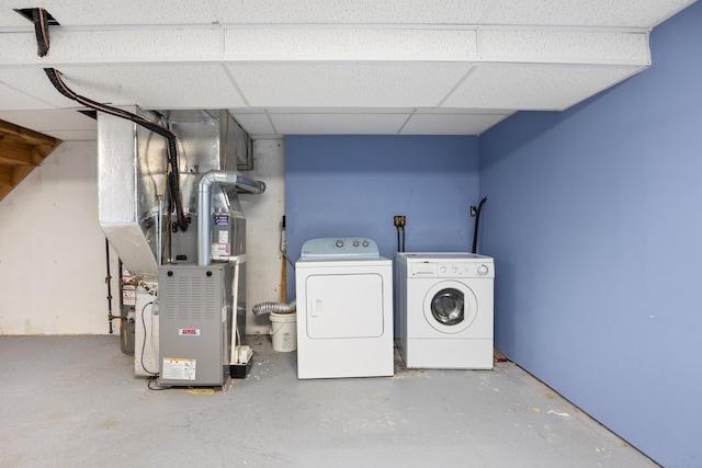 clothes washing area featuring washing machine and dryer, heating unit, and laundry area