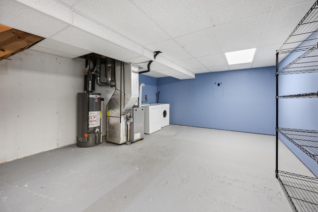 finished basement with heating unit, washer and clothes dryer, gas water heater, and a paneled ceiling