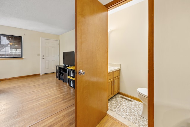 interior space with wood finished floors, visible vents, toilet, and baseboards