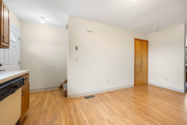 kitchen with light countertops, visible vents, white dishwasher, light wood-type flooring, and baseboards