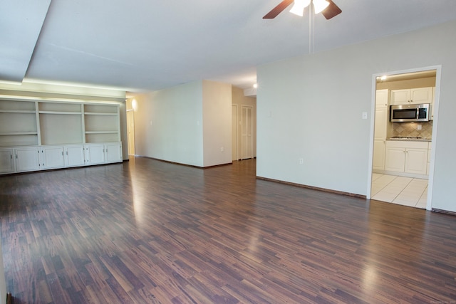 unfurnished living room featuring baseboards, wood finished floors, and a ceiling fan