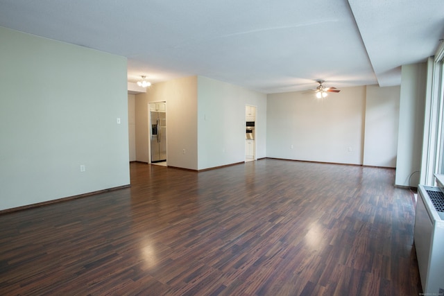 unfurnished living room with dark wood-type flooring, baseboards, and a ceiling fan