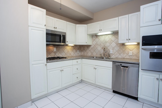 kitchen featuring tasteful backsplash, light tile patterned floors, white cabinets, stainless steel appliances, and a sink