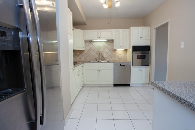kitchen featuring a ceiling fan, tasteful backsplash, appliances with stainless steel finishes, a sink, and light tile patterned floors