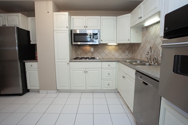 kitchen with light tile patterned floors, backsplash, a sink, and stainless steel appliances