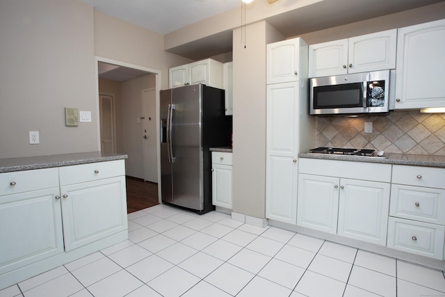 kitchen with white cabinetry, light tile patterned floors, backsplash, and stainless steel appliances