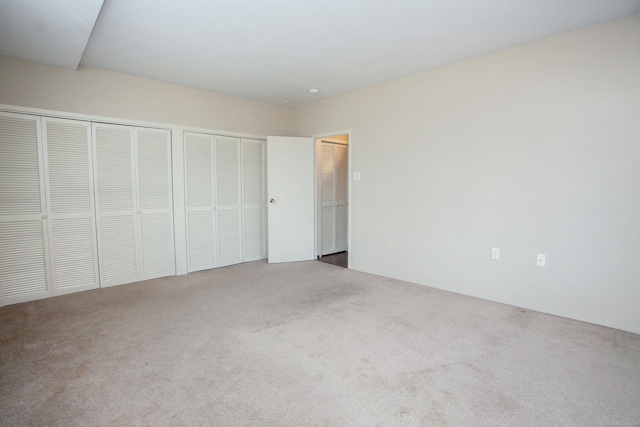 unfurnished bedroom featuring two closets and carpet flooring