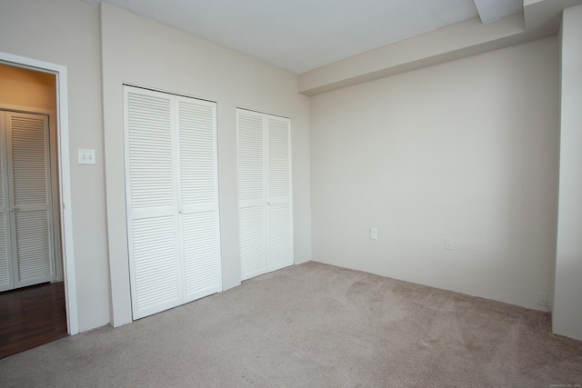 unfurnished bedroom with multiple closets and carpet flooring