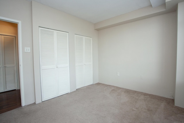 unfurnished bedroom featuring carpet and multiple closets