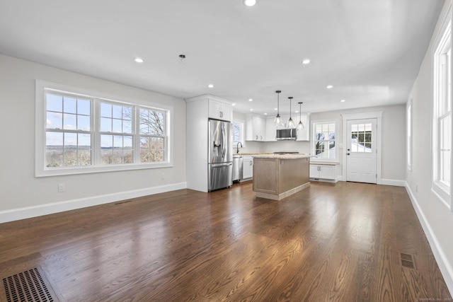 unfurnished living room featuring visible vents, a sink, recessed lighting, baseboards, and dark wood-style flooring