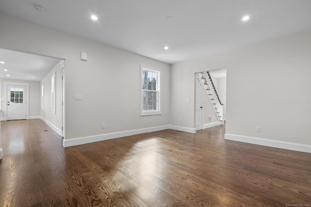 unfurnished living room featuring dark wood-type flooring, stairway, recessed lighting, and baseboards