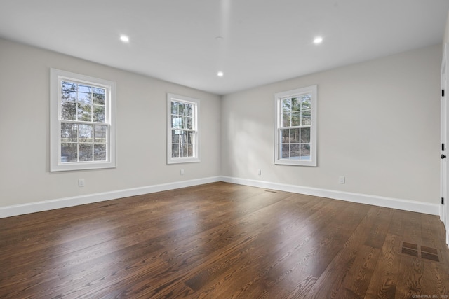 unfurnished room with visible vents, baseboards, a healthy amount of sunlight, and dark wood-style floors