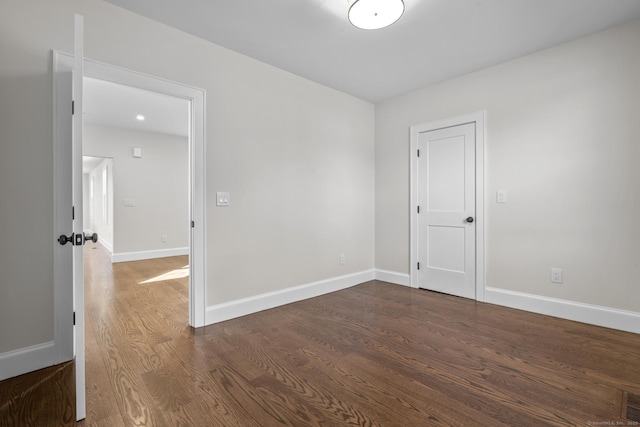 spare room featuring baseboards and dark wood-style flooring